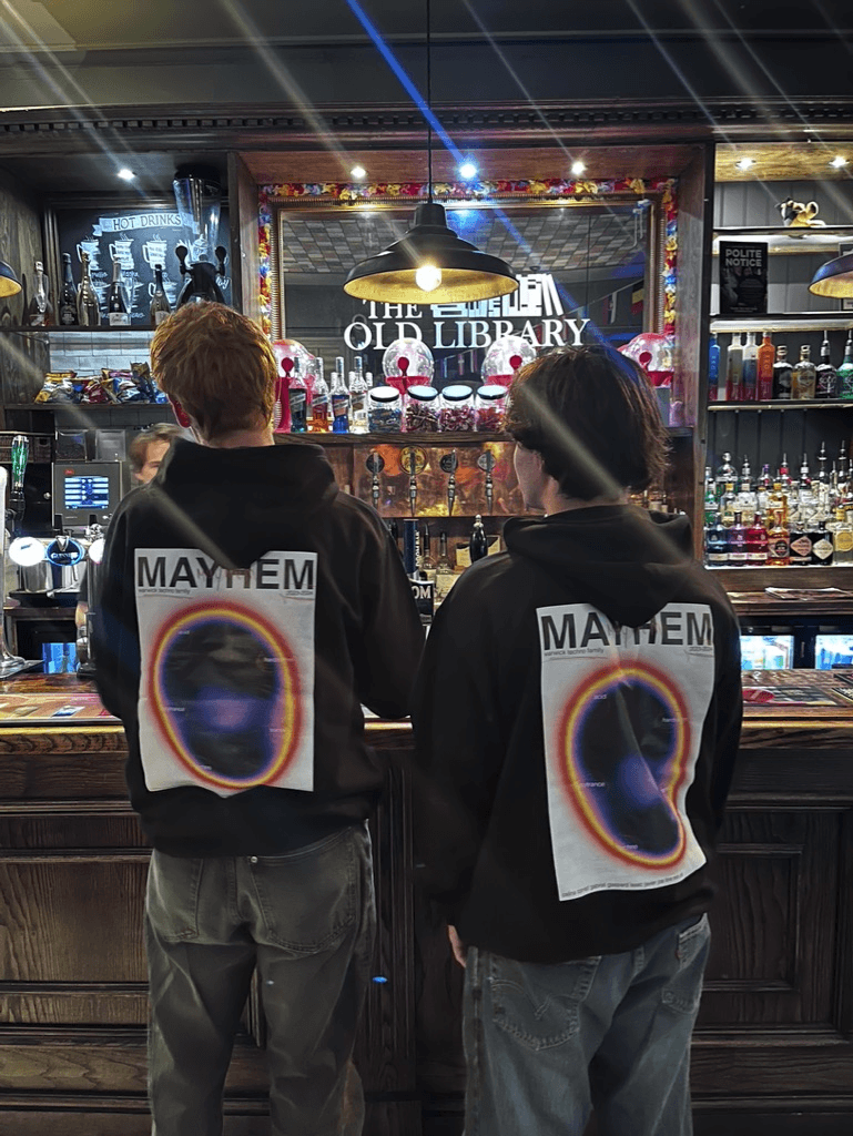 Two people wearing Mayhem hoodies at a bar